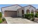 Inviting stucco home featuring a two-car garage, complemented by lush green landscaping and a concrete driveway at 20698 W Meadowbrook Ave, Buckeye, AZ 85396