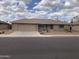 Tan home showcasing a desert landscaped front yard, stone accents, and a two-car garage, under a bright, partly cloudy sky at 2152 S Olivewood --, Mesa, AZ 85209