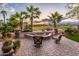 Inviting backyard with a cozy fire pit, mature palm trees, and views of the lush green golf course at 22912 N San Ramon Ct, Sun City West, AZ 85375