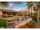Serene backyard setting with a fire pit, palm trees, artificial grass, and a covered patio dining area at 22912 N San Ramon Ct, Sun City West, AZ 85375