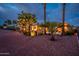 Charming backyard featuring a fire pit, desert landscaping, and illuminated palm trees, creating a tranquil oasis at 22912 N San Ramon Ct, Sun City West, AZ 85375
