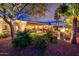 Lush backyard with mature trees, manicured landscaping, an outdoor kitchen, and a cozy fire pit area at 22912 N San Ramon Ct, Sun City West, AZ 85375