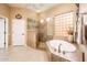 This bathroom boasts a soaking tub, neutral tile, vanity, and walk-in glass shower at 22912 N San Ramon Ct, Sun City West, AZ 85375