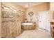 Bathroom featuring a soaking tub, glass walk-in shower, neutral tiling, and vanity at 22912 N San Ramon Ct, Sun City West, AZ 85375