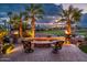 Relaxing outdoor fire pit with chairs surrounded by palm trees and beautiful golf course view at 22912 N San Ramon Ct, Sun City West, AZ 85375