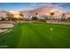 Picturesque golf course view with a lush green fairway, a red flag, mature palm trees, and a stunning sunset at 22912 N San Ramon Ct, Sun City West, AZ 85375