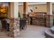 Inviting outdoor kitchen area with built-in grill, bar seating, and stone accents at 22912 N San Ramon Ct, Sun City West, AZ 85375