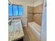 Bright bathroom featuring a granite countertop, a large window, and a tiled bathtub at 2533 E Flower St, Phoenix, AZ 85016