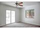 Bedroom with a ceiling fan, window, sliding glass door and neutral carpeting provides a cozy and bright living space at 2533 E Flower St, Phoenix, AZ 85016