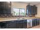 Well-lit kitchen featuring dark cabinets, stainless steel appliances, and a window above the sink at 2939 W Sunshine Butte Dr, San Tan Valley, AZ 85144