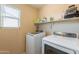 Efficient laundry room with modern washer and dryer, shelving for storage, and natural light from a window at 2939 W Sunshine Butte Dr, San Tan Valley, AZ 85144