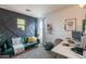 Stylish living room featuring a decorative accent wall, cozy green futon, and plenty of natural light at 2939 W Sunshine Butte Dr, San Tan Valley, AZ 85144