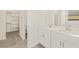 Bright bathroom featuring dual sinks, white cabinets, and a walk-in closet at 37325 W San Clemente St, Maricopa, AZ 85138