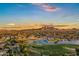 Aerial view of a community at sunset, showcasing a golf course, lake, and mountain views at 3842 E Alameda Ln, Gilbert, AZ 85298