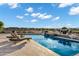 Lounge chairs and a waterfall feature highlight this stunning backyard pool area overlooking the water at 3842 E Alameda Ln, Gilbert, AZ 85298