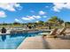 Beautiful backyard pool area with a waterfall feature and lounge chairs overlooking a serene lake at 3842 E Alameda Ln, Gilbert, AZ 85298