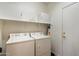 Clean laundry room with white washer and dryer, shelving, and a white door at 40055 N High Noon Way, Anthem, AZ 85086