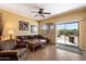 Comfortable living room featuring a plush brown sectional sofa, a ceiling fan, and sliding glass doors to the backyard at 40055 N High Noon Way, Anthem, AZ 85086