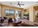 Inviting living room features a TV with a fireplace stand, a comfortable sofa, and a ceiling fan at 40055 N High Noon Way, Anthem, AZ 85086