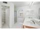 Bright bathroom featuring dual sinks, sleek tile flooring, and a glass-enclosed shower at 4446 E Woodridge Dr, Phoenix, AZ 85032