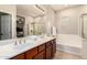 Bright bathroom featuring a double vanity, a large mirror, a bathtub, and a glass-walled shower at 5436 W Chisum Trl, Phoenix, AZ 85083