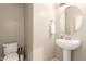 Clean, minimalist half-bathroom featuring a pedestal sink, round mirror, and updated toilet at 5436 W Chisum Trl, Phoenix, AZ 85083