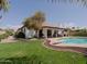 Beautiful backyard view with a pristine pool, covered patio, well-maintained lawn, and mature trees, ideal for entertaining at 5719 E Paradise Ln, Scottsdale, AZ 85254