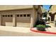 Attached garages featuring paneled doors on a tan building with neatly landscaped borders at 7675 E Mcdonald Dr # 107, Scottsdale, AZ 85250