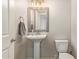 Clean half bathroom with a pedestal sink, framed mirror, and modern fixtures, creating a simple and elegant space at 8026 S 6Th Dr, Phoenix, AZ 85041