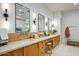 Long Primary bathroom featuring double sinks, wood cabinets, tile backsplash, and three large mirrors at 8220 E Sharon Dr, Scottsdale, AZ 85260