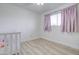 A serene bedroom with a white crib, soft pink curtains, and ample natural light creating a peaceful atmosphere at 1059 E 9Th Ave, Mesa, AZ 85204