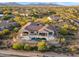 Expansive desert home featuring an outdoor pool, covered patio, and lush desert landscaping at 10799 E Florence Way, Scottsdale, AZ 85262