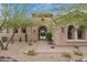 Inviting arched entryway with a desert landscape, creating a warm and welcoming feel to this home at 10799 E Florence Way, Scottsdale, AZ 85262