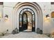 Grand arched entryway with custom iron gate, enhanced by exterior lighting and desert landscaping at 10799 E Florence Way, Scottsdale, AZ 85262