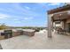Covered patio with an outdoor kitchen area, lounge seating and views of the pool and landscape at 10799 E Florence Way, Scottsdale, AZ 85262