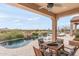 Covered patio offering lounge seating, views of the pool area, desert landscape and an outdoor kitchen at 10799 E Florence Way, Scottsdale, AZ 85262