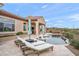 Inviting backyard featuring a pool, lounge chairs, and an outdoor kitchen area under a bright, blue sky at 10799 E Florence Way, Scottsdale, AZ 85262