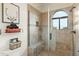 Modern walk-in shower with glass door, and decorative tile work and adjacent shelf at 10799 E Florence Way, Scottsdale, AZ 85262