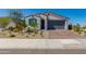 Charming single-story home featuring a gray garage door, brick driveway, and desert landscaping at 11738 S 173Rd Ln, Goodyear, AZ 85338