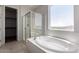 Bright bathroom with a soaking tub, glass-enclosed shower, and a large window for natural light at 13749 W Amberwing St, Peoria, AZ 85383