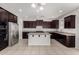 Open kitchen features dark wood cabinets, granite countertops, stainless appliances and a kitchen island at 13749 W Amberwing St, Peoria, AZ 85383