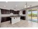 Kitchen features dark wood cabinets, granite countertops, island and large sliding glass doors to backyard at 13749 W Amberwing St, Peoria, AZ 85383