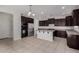 Spacious kitchen featuring dark wood cabinetry, granite countertops, stainless appliances, and tile flooring at 13749 W Amberwing St, Peoria, AZ 85383