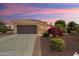 Charming home featuring a two-car garage, desert landscaping, and lush colorful shrubs at 13841 W Nogales Dr, Sun City West, AZ 85375