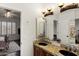 Bathroom with double sinks, wooden vanity, decorative mirror and doorway to bedroom and toilet at 1515 E Saratoga Ct, Gilbert, AZ 85296
