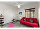 Bright room with a red futon, workout bench, gray tile floors, and a ceiling fan with light fixture at 1515 E Saratoga Ct, Gilbert, AZ 85296