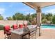 Outdoor kitchen area with built-in grill, granite counters, refrigerator, swing and pool access at 1515 E Saratoga Ct, Gilbert, AZ 85296