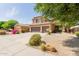 Two-story home with desert landscaping, green foliage, a three-car garage, and a long driveway at 16228 W Crocus Dr, Surprise, AZ 85379