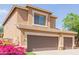 Close up of a two-story home with a three-car garage, desert landscaping, and green foliage at 16228 W Crocus Dr, Surprise, AZ 85379