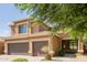 Two-story home with a three-car garage and desert landscaping with green foliage at 16228 W Crocus Dr, Surprise, AZ 85379